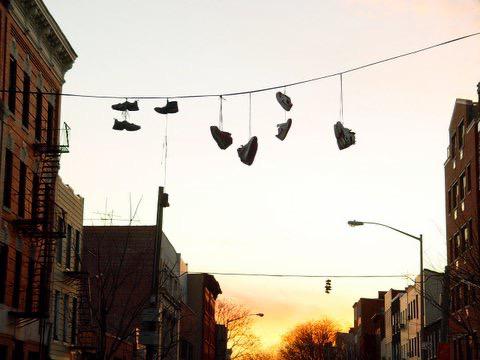 The origin of an urban mystery: why do shoes hang from electrical cables?